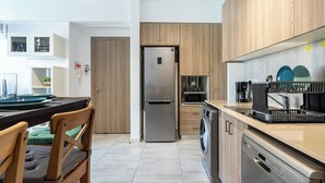 Een moderne keuken met een koelkast, magnetron, vaatwasser en koffiezetapparaat.