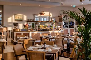 En restaurant med fletmøbler, et buffetområde og en stor stueplante.