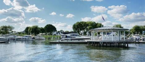 A marina with boats docked, a gazebo, and a clear sky.