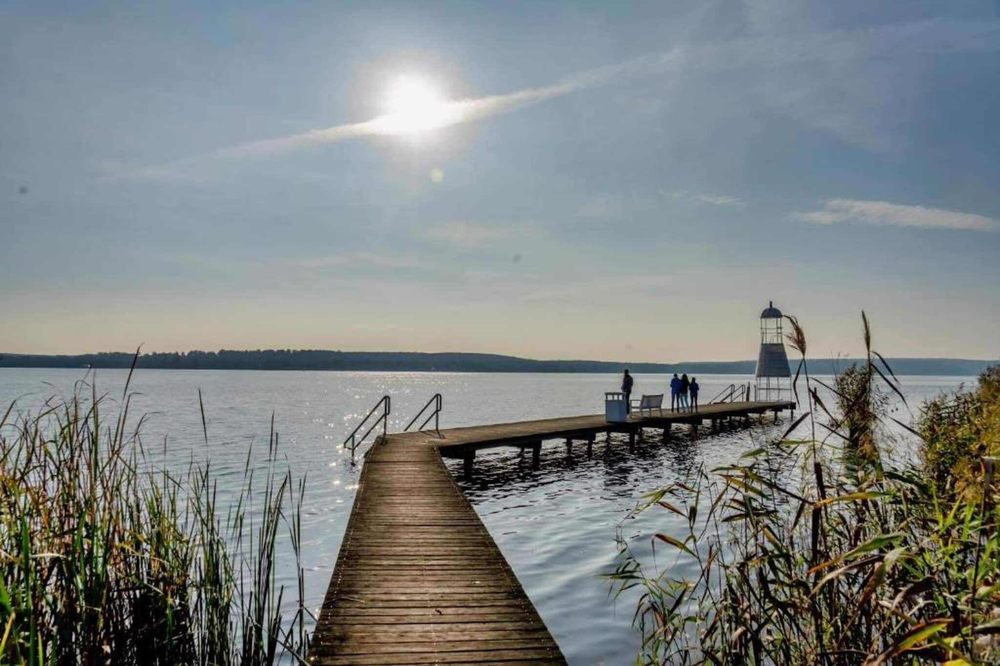 A wooden pier extending into calm water with a lighthouse in the distance.