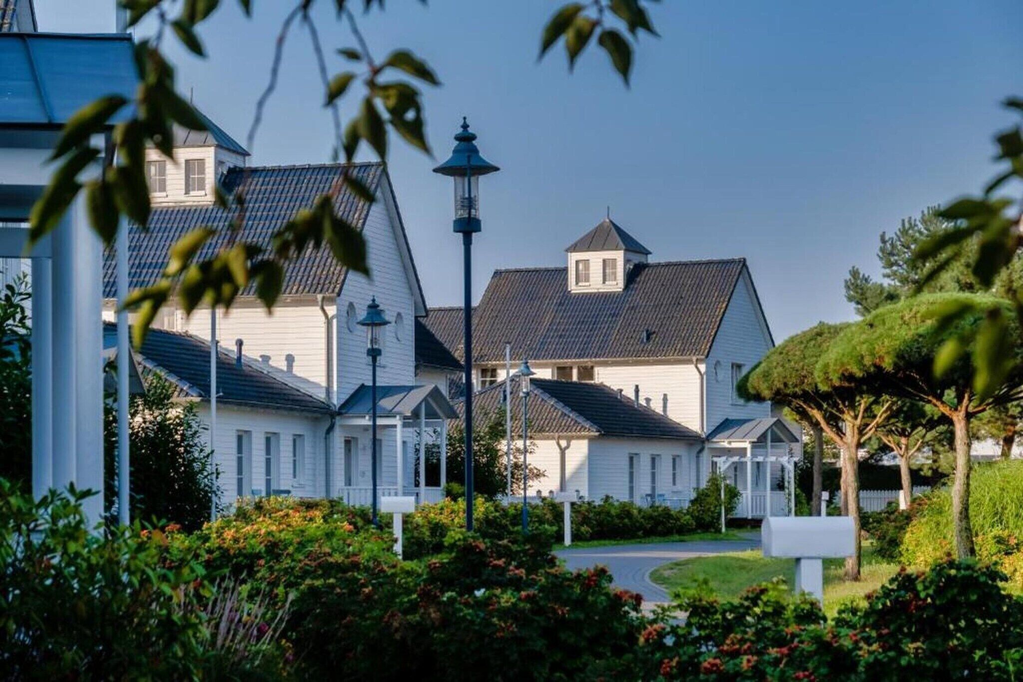 A row of white houses with dark roofs, a street lamp, and a mailbox.
