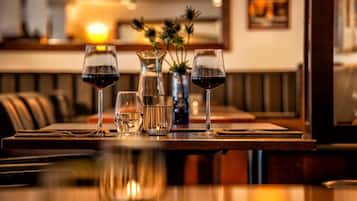 A restaurant table with three wine glasses, a pitcher, and a vase with flowers.