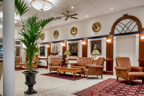 A lobby with a high ceiling, a fan, multiple clocks, and a seating area with sofas and armchairs. - Schwielowsee Hotel Executive Room with balcony (Werder)
