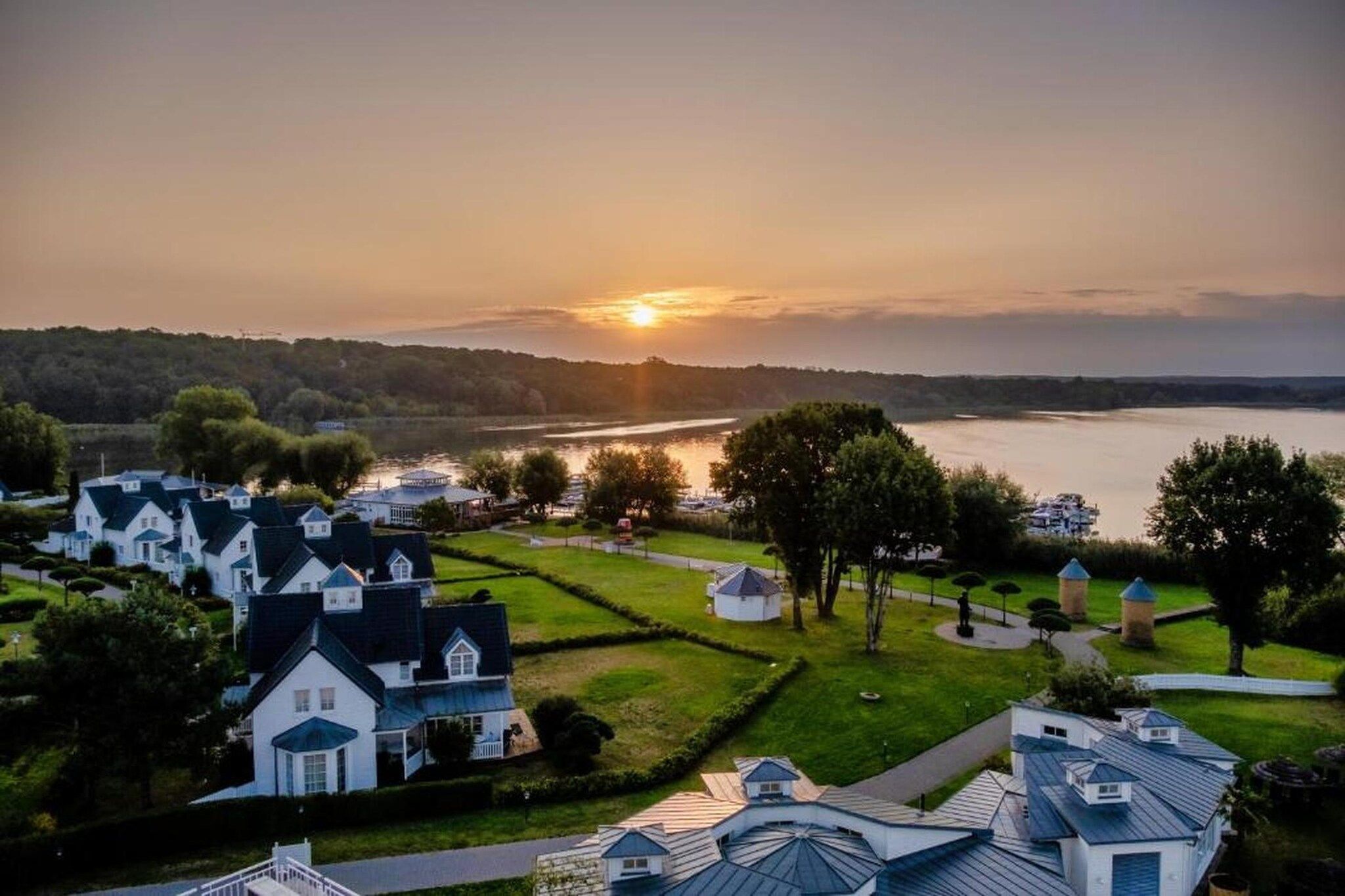 A residential area with houses, a body of water, and a sunset.