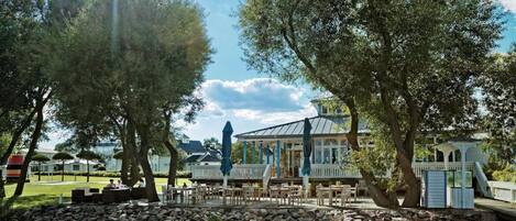 A lakeside restaurant with outdoor seating, a covered patio, and a view of the water.