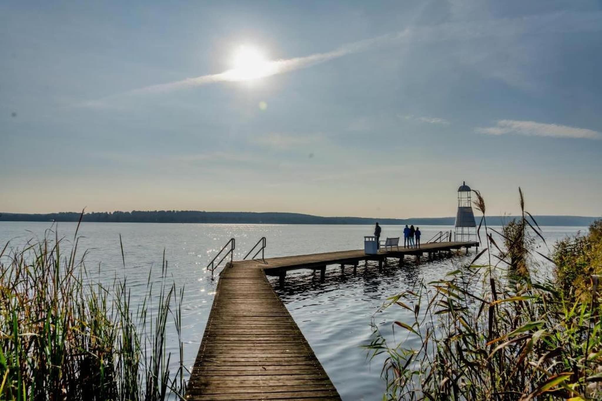 A wooden pier extending into calm water with a lighthouse in the distance.