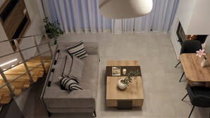 A modern living room with a sofa, coffee table, and dining area. - NISIS II – Urban Loft Surrounded by Nature (Perani)
