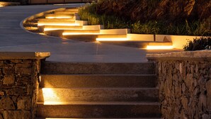 A set of outdoor stairs leading to a modern building with a stone wall on one side and a grassy area on the other. - NISIS II – Urban Loft Surrounded by Nature (Perani)