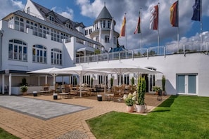 Ein Hotel mit Innenhof, Terrassenmöbeln und Flaggen.