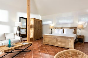 Ein Schlafzimmer mit einem großen Bett, einem Holzschrank, einem weißen Sofa und einem kleinen Tisch mit Tablett.