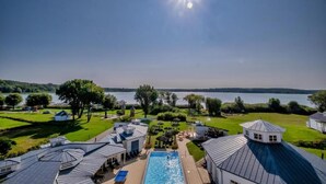 A swimming pool with a view of a lake and surrounding buildings. - Sunday Resort Schwielowsee Suite (Werder)