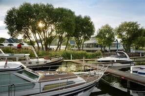 A marina with boats docked, surrounded by trees and a building with a blue roof. - Sunday Resort Schwielowsee Suite (Werder)