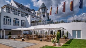A hotel with a courtyard patio, outdoor seating, and flags. - Sunday Resort Schwielowsee Suite (Werder)