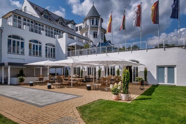 A hotel with a courtyard patio, outdoor seating, and flags. - Sunday Resort Schwielowsee Suite (Werder)