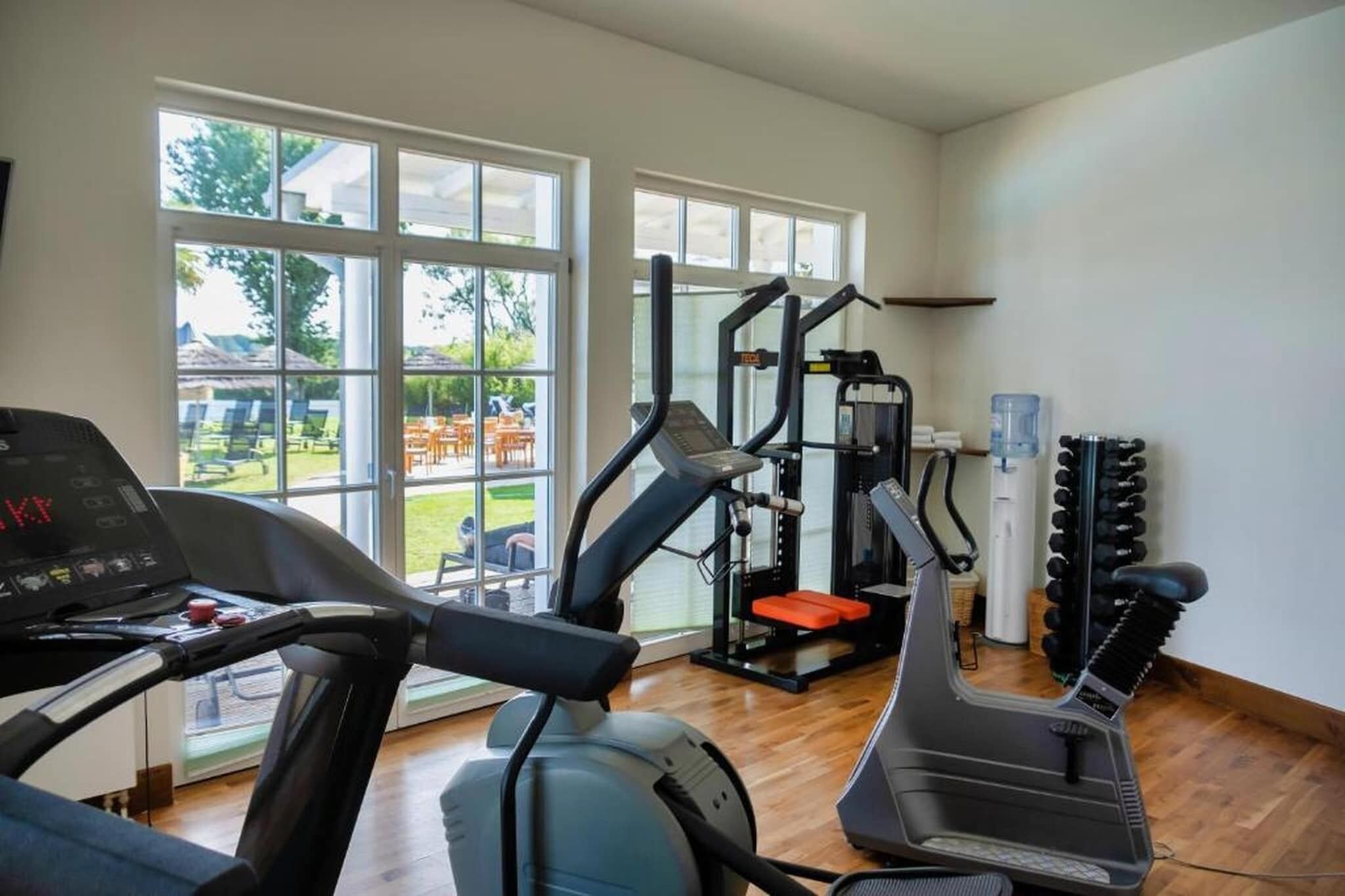 Une salle de sport équipée de tapis de course, d’une machine de musculation et d’un distributeur d’eau.