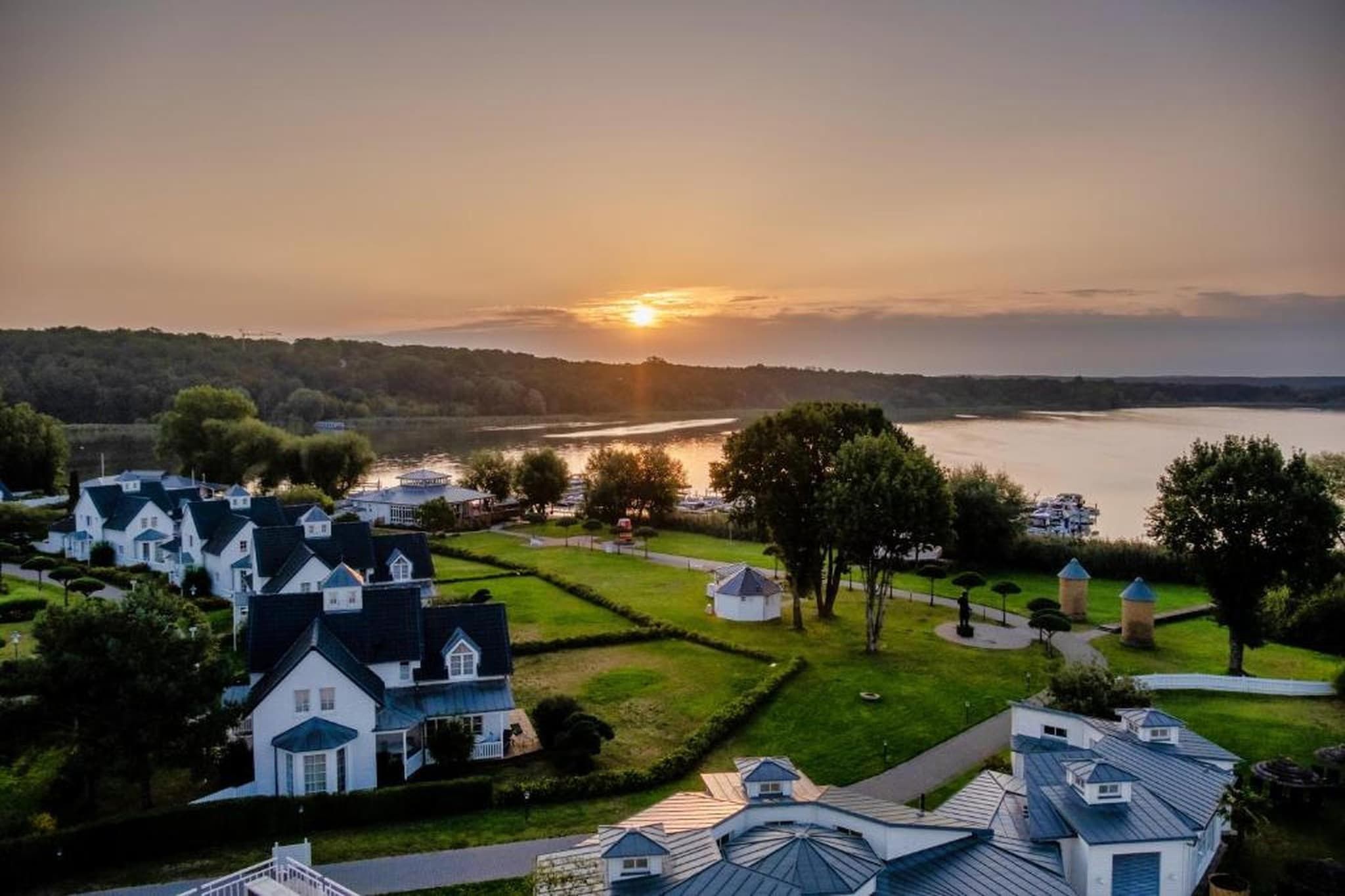 A residential area with houses, a river, and a sunset.