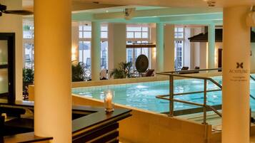 A hotel pool area with a view of the sea, a reception desk, and a sign indicating the pool's depth.