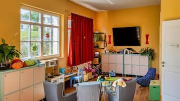 A room with a large window, a television, a cabinet, and a chair.
