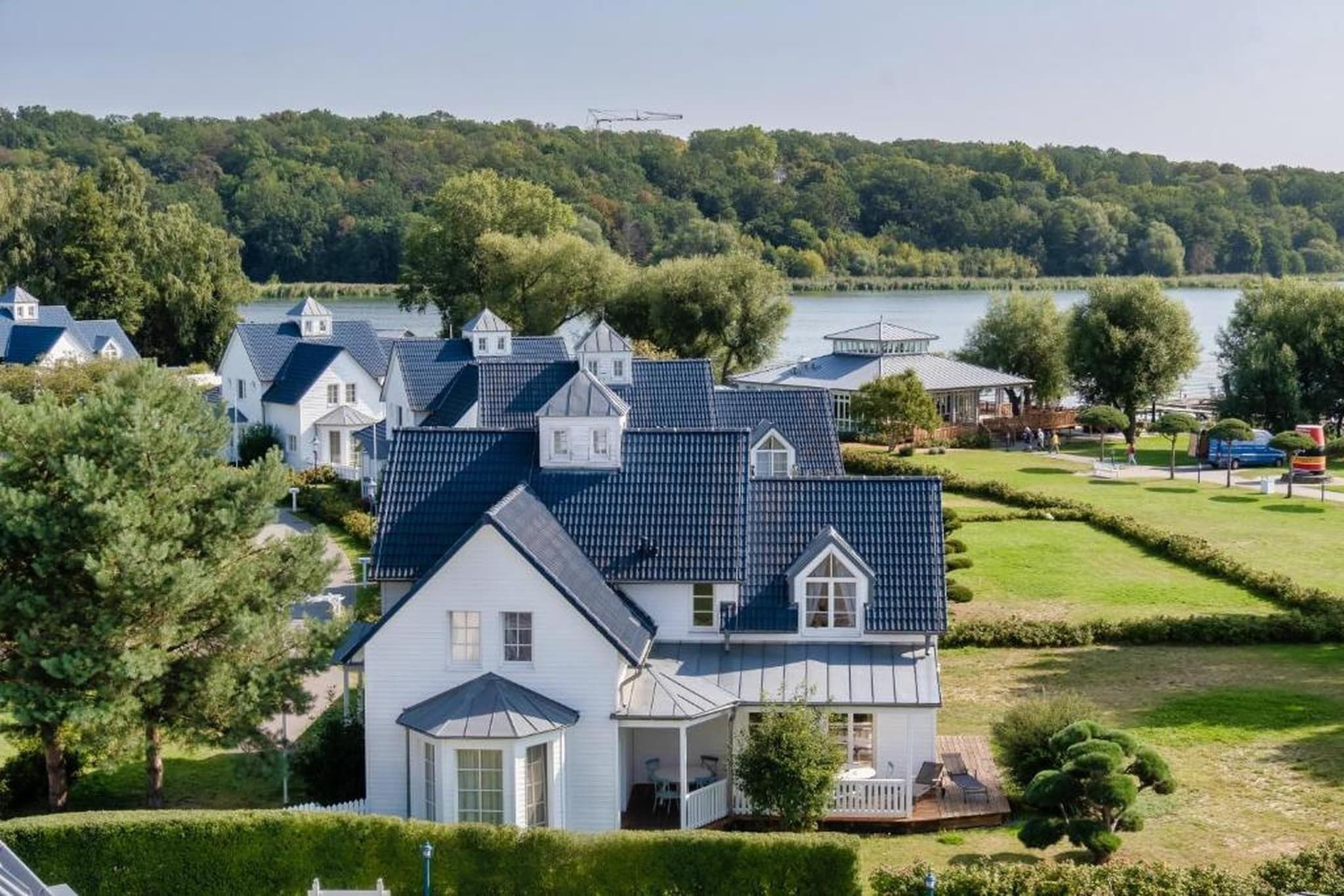 Een woonwijk met huizen, een meer en een beboste heuvel op de achtergrond.