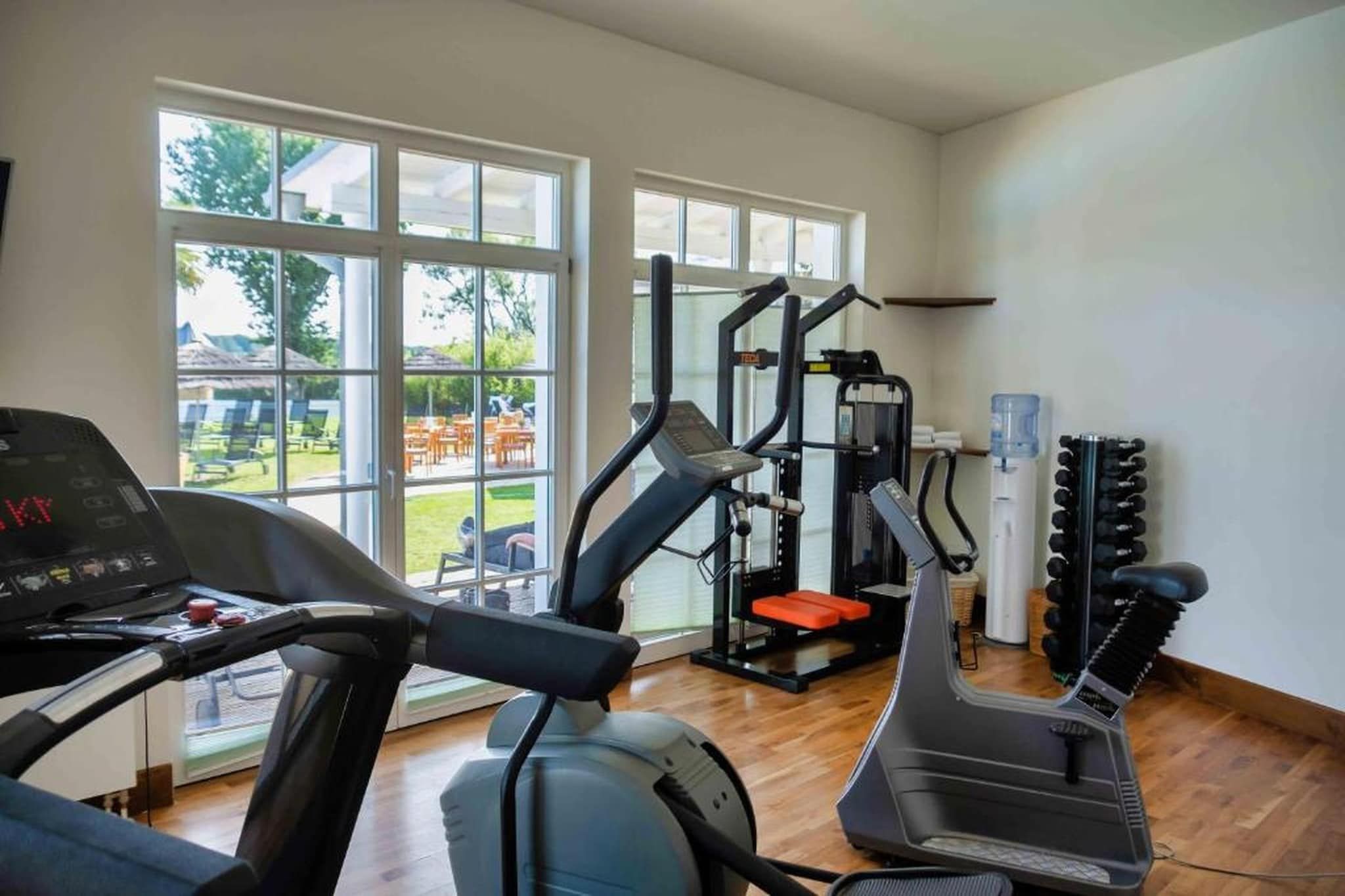 A gym with cardio equipment, weight machines, and a view of the outdoors.