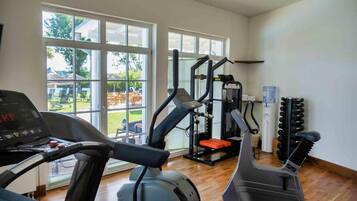 A gym with cardio equipment, weight machines, and a view of the outdoors.