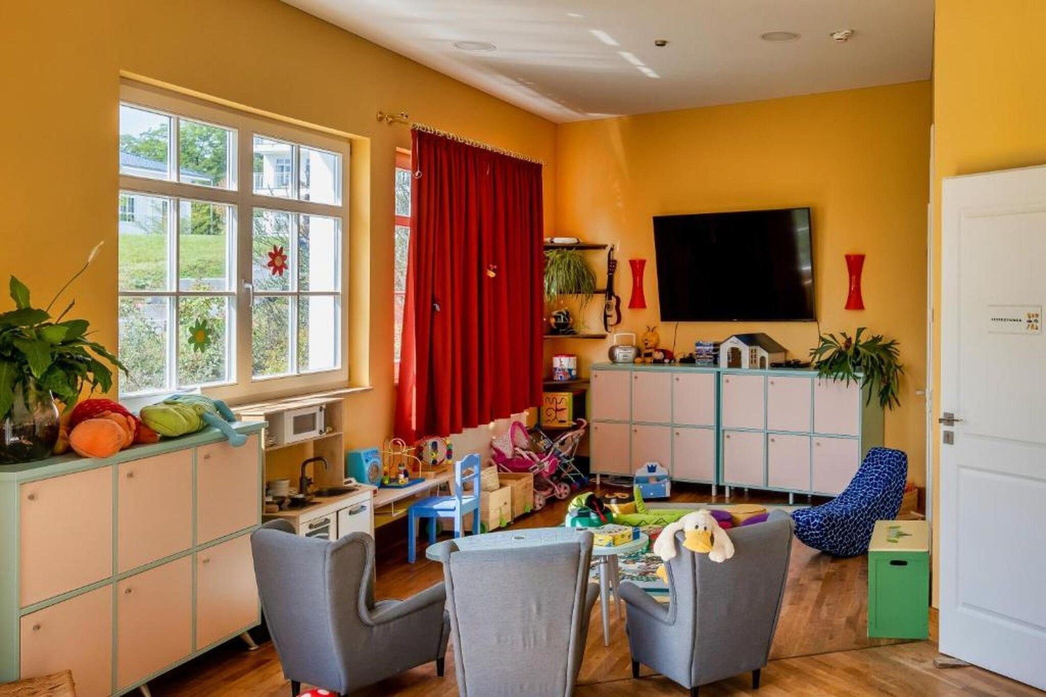 A room with a window, a television, a cabinet, and a chair.
