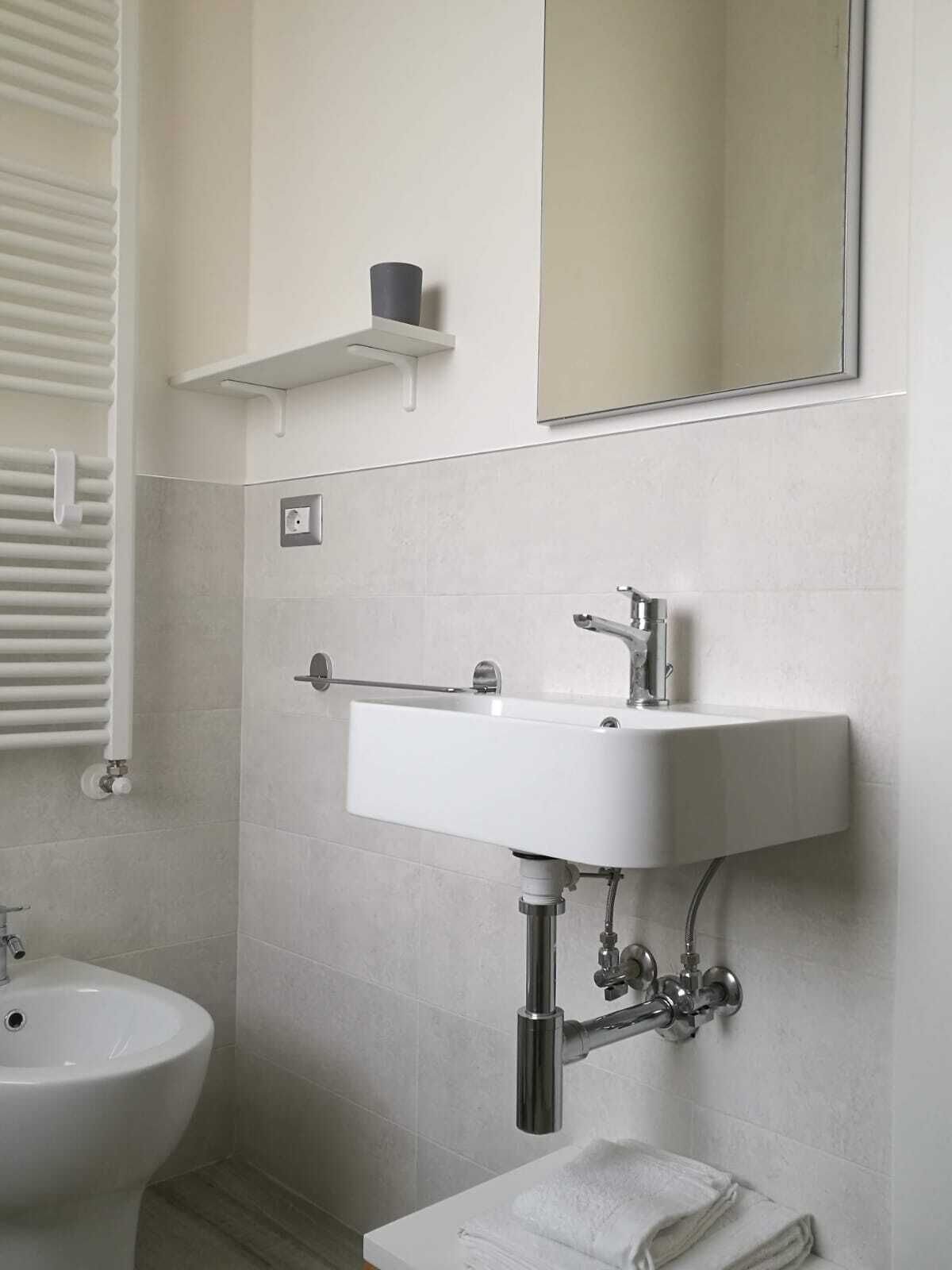 A bathroom with a white sink, a mirror, a towel rack, and a toilet.