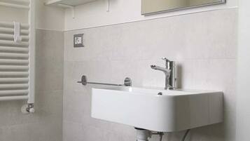 Ein Badezimmer mit Waschbecken, Spiegel, Handtuchhalter und Toilette.