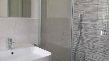 A modern bathroom with a white sink, a glass shower enclosure, and a mirror.