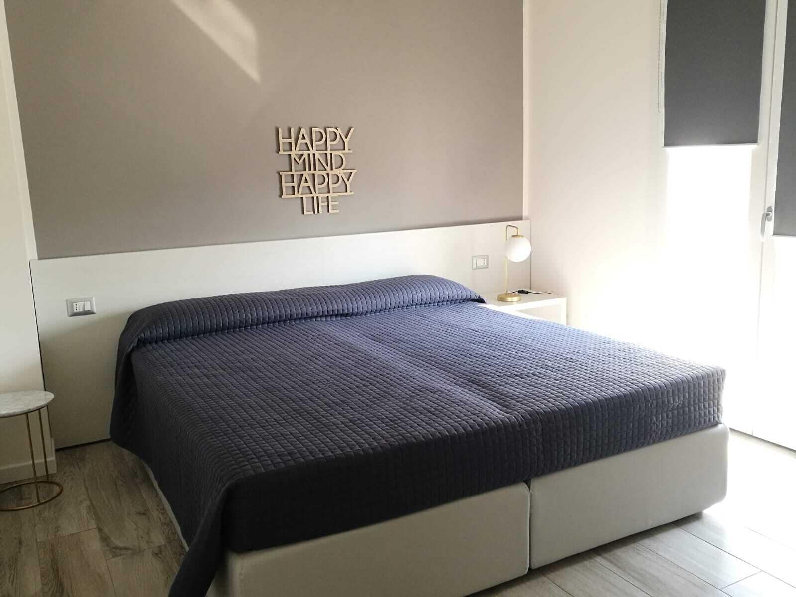 Un dormitorio moderno con una cama, una mesita de noche y una pared con una cita motivacional.