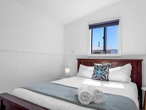 A hotel room with a bed, a bedside lamp, a window with a view, and a bench. - Kulang Retreat - A peaceful retreat for fun and relaxation (Broke)
