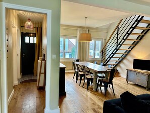 A dining area with a wooden table and chairs, a staircase, and a view of the outside. - House with garden, 400m from the beach, all on foot, private parking (Wimereux)