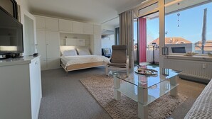Un hotel moderno con cama, una mesa de centro de cristal, un sofá y vistas al exterior.