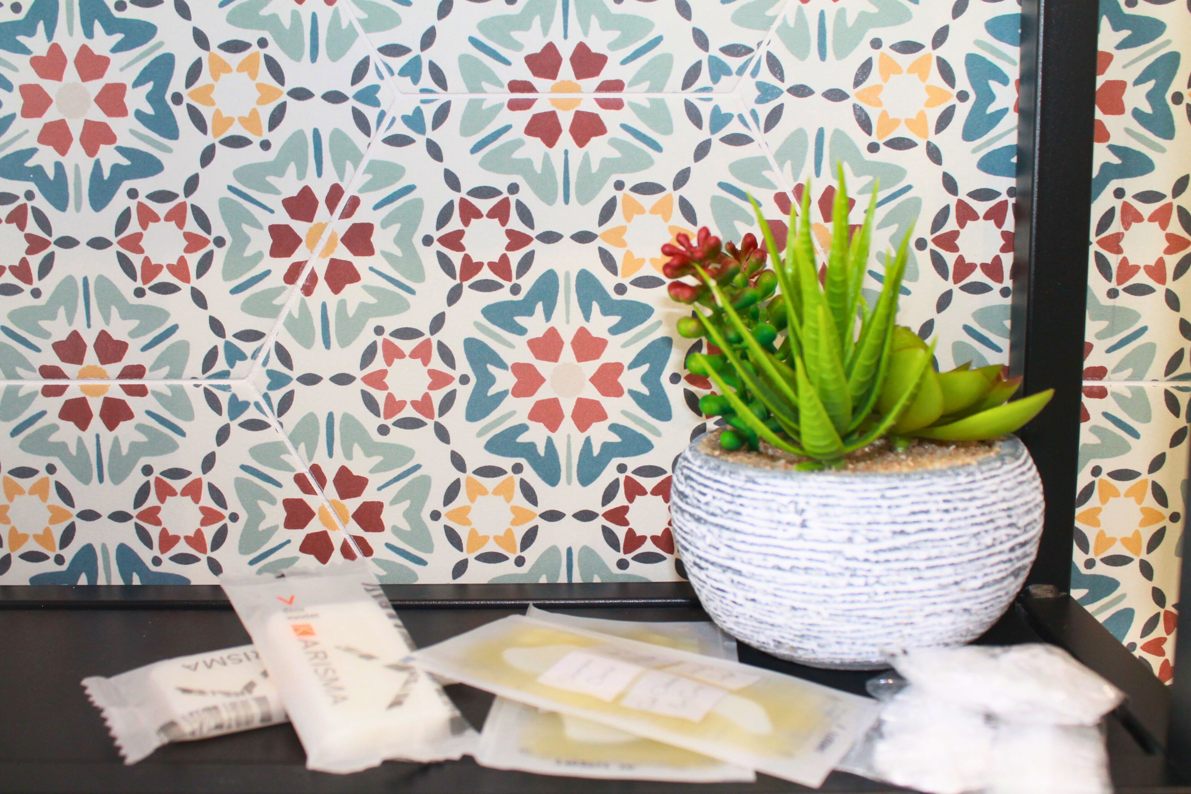 A potted plant on a table with patterned wallpaper in the background.
