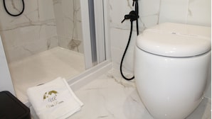 Une salle de bain avec des toilettes blanches, un espace douche et une serviette ornée d’un logo.