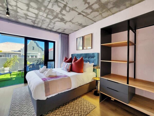 Ett modernt hotellrum med en stor säng, utsikt över omgivningarna och inbyggda hyllor.