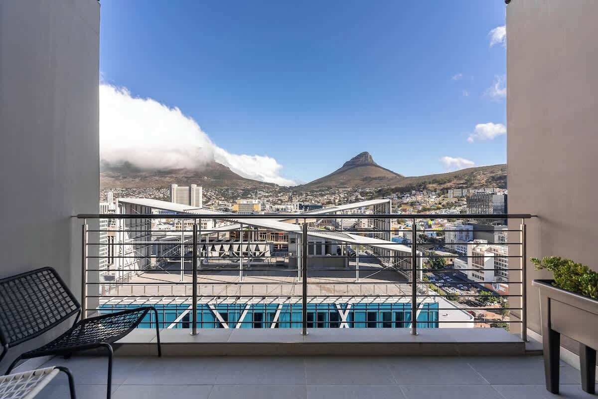 Un balcon offrant une vue sur la ville, une montagne et une piscine.