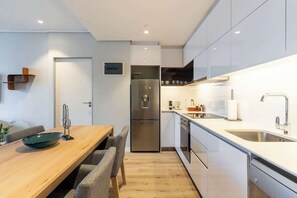Eine moderne Küche mit Einbauofen, Edelstahlgeräten und einem Holzespeisetisch mit Stühlen.