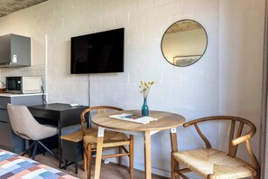 A room with a bed, a desk, a chair, a round table, a TV, and a mirror. - Seaside Star - retreat w/ A/C, patio, pool (Cape Town)