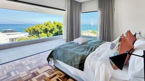 A modern bedroom with a large bed, a view of the sea, and a balcony. - Villa Rohalya: Sensational designer hideaway / 6BR (Cape Town)