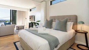 Een moderne slaapkamer met een groot bed, een sofa, een bijzettafeltje en uitzicht op de omgeving.