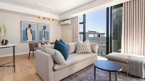Een moderne woonkamer met een bank, een klein tafeltje, een stoel en kunst aan de muur.