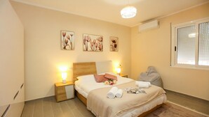 Un dormitorio con cama, lámparas de noche, mesita de noche, ventana con persianas y decoración en la pared.