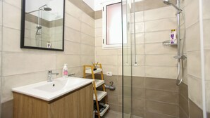 Un baño con lavamanos, espejo, ducha y estanterías.