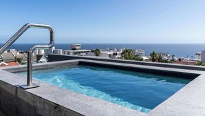 Ein Pool auf dem Dach mit freiem Blick auf das Meer und die Stadtlandschaft.