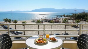 A balcony with a table set for breakfast, overlooking a beach and the sea. - Luna Sea View Apartment 5 Floor (Vlorë)
