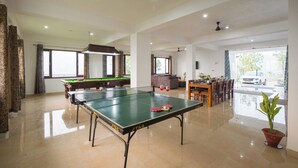 A spacious indoor area with a ping pong table, a pool table, and a dining area with chairs and a table. - Alaya Stays Querencia 5BHK with HillView (Kasauli)