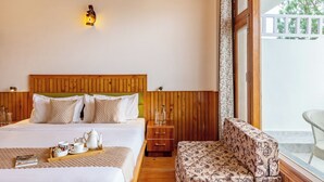 A bedroom with a wooden headboard, a bedside table with a lamp, a sofa, and a balcony view. - Alaya Stays Querencia 5BHK with HillView (Kasauli)