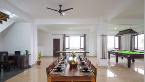 A dining area with a pool table, a ceiling fan, and a view of the outside. - Alaya Stays Querencia 5BHK with HillView (Kasauli)
