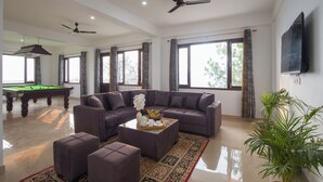 A spacious living room with a pool table, a sofa, a coffee table, and a television. - Alaya Stays Querencia 5BHK with HillView (Kasauli)